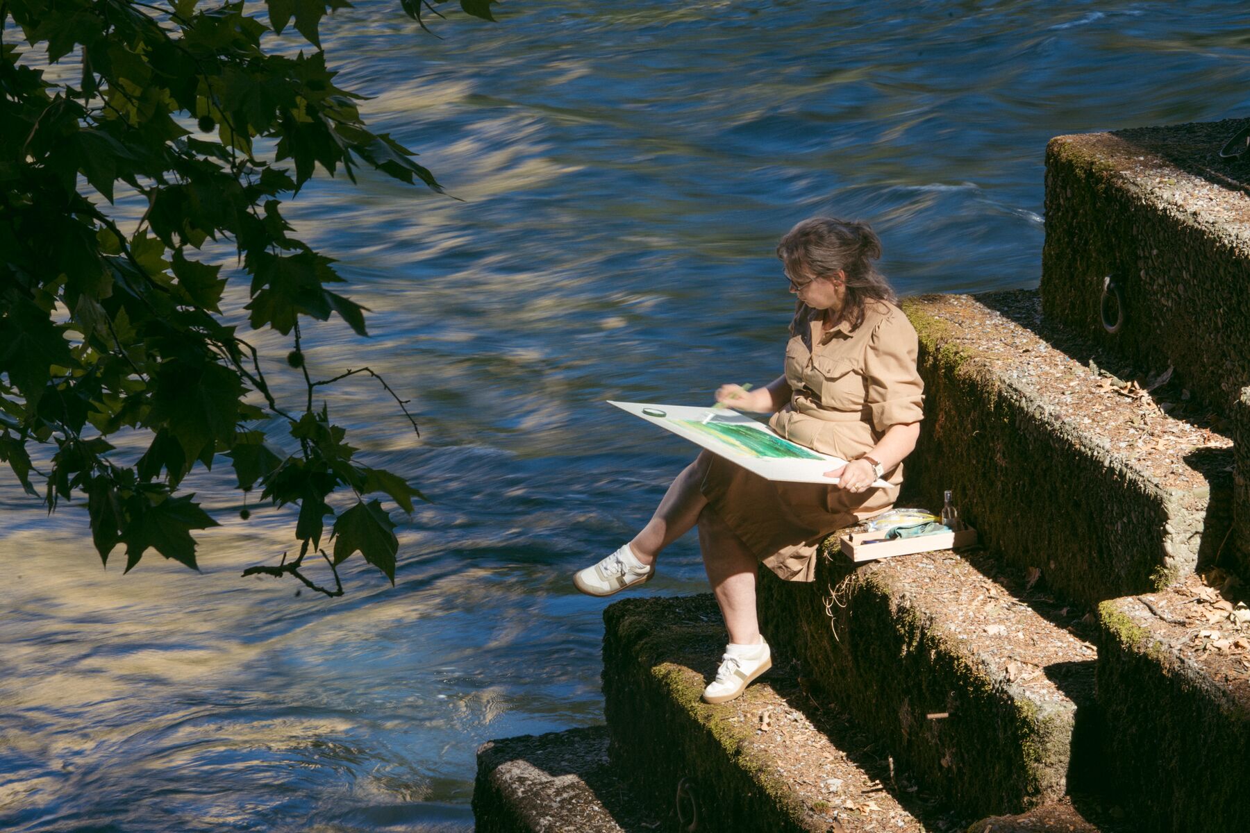 Marina Tschan malt auf einer Treppe am Fluss