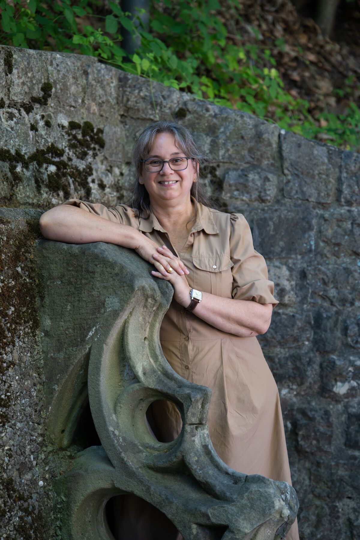 Marina Tschan lehnt lächelnd an einer Steinmauer